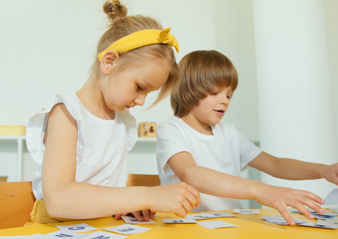 Two young children engaged in a fun learning activity indoors, focusing on letters.