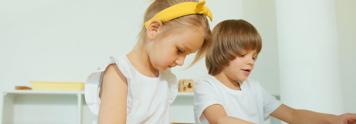 Two young children engaged in a fun learning activity indoors, focusing on letters.