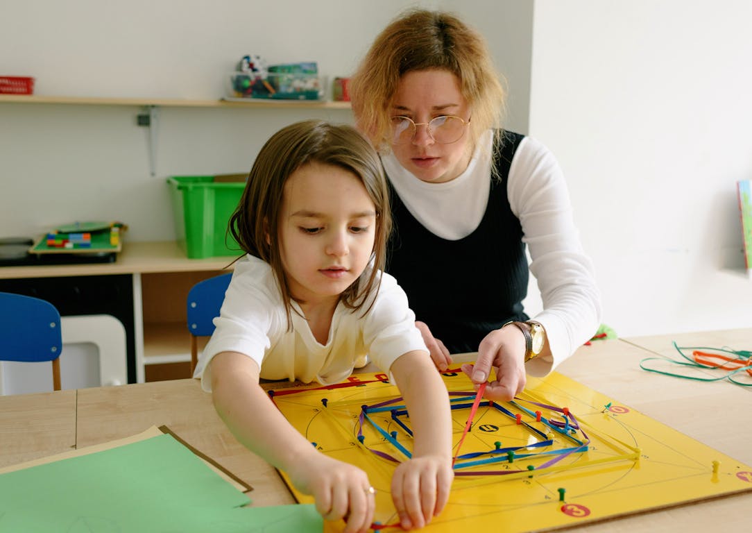 A child and teacher work together on an educational activity in a classroom setting.
