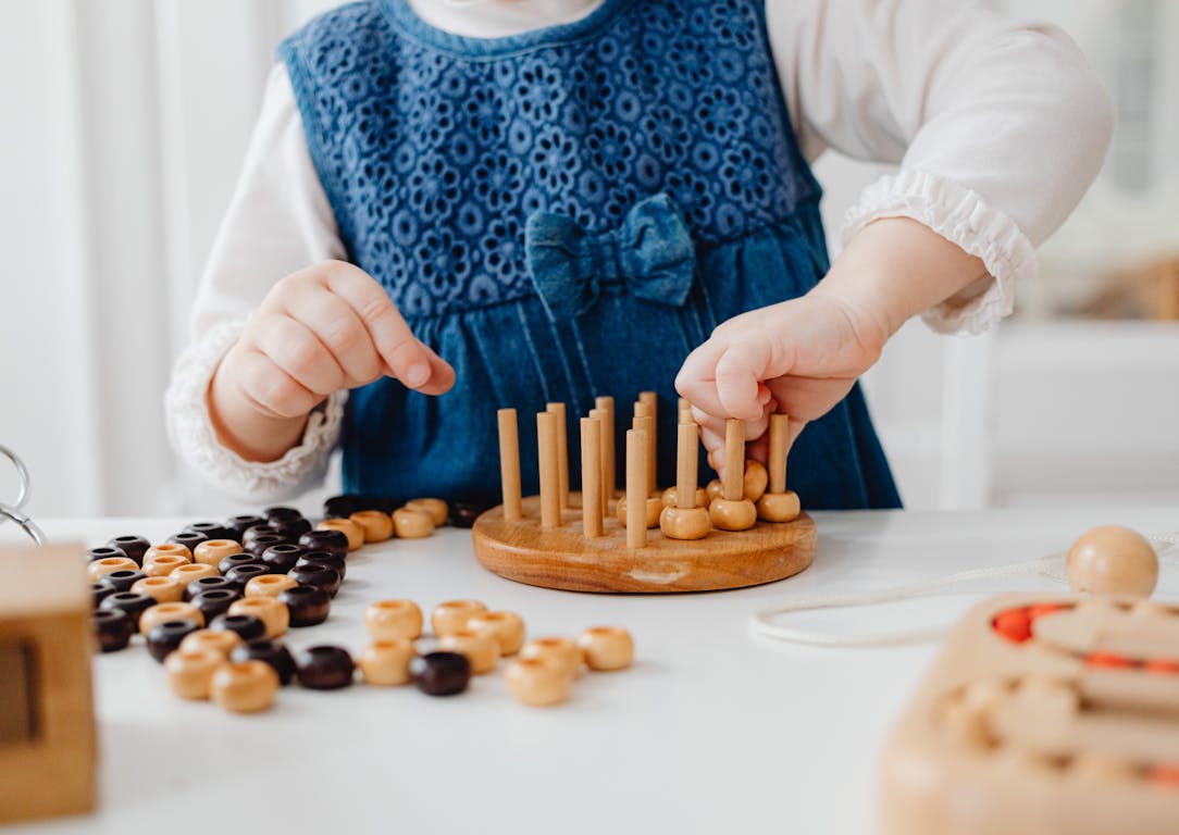 A child interacts with a wooden sorting toy, developing fine motor skills and learning through play.