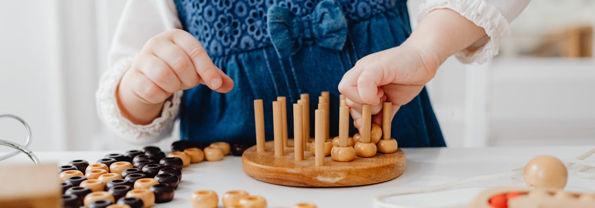 A child interacts with a wooden sorting toy, developing fine motor skills and learning through play.