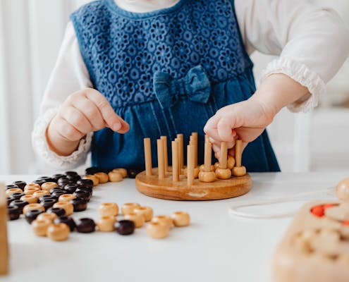 A child interacts with a wooden sorting toy, developing fine motor skills and learning through play.