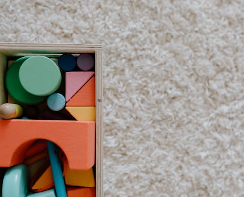 A set of colorful wooden blocks on a carpet, ideal for children's creative play.